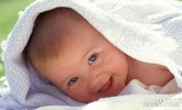 bébé sourit sous une couverture